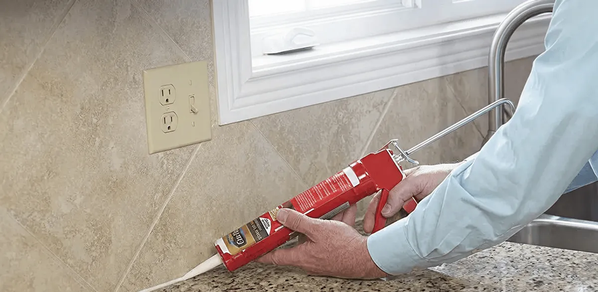 Handyman applying caulk along a kitchen backsplash and countertop seam in Chattanooga, TN